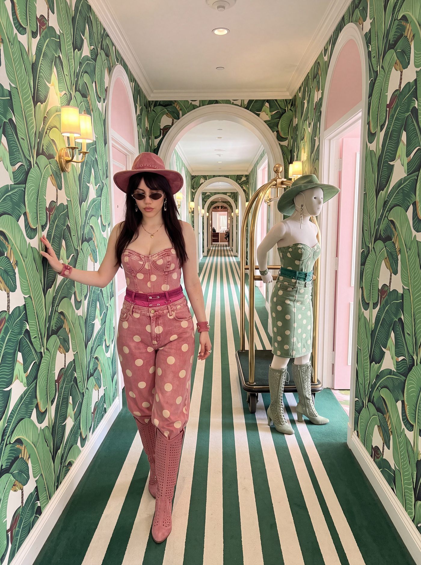 A woman and a mannequin in matching green print in a papered corridor