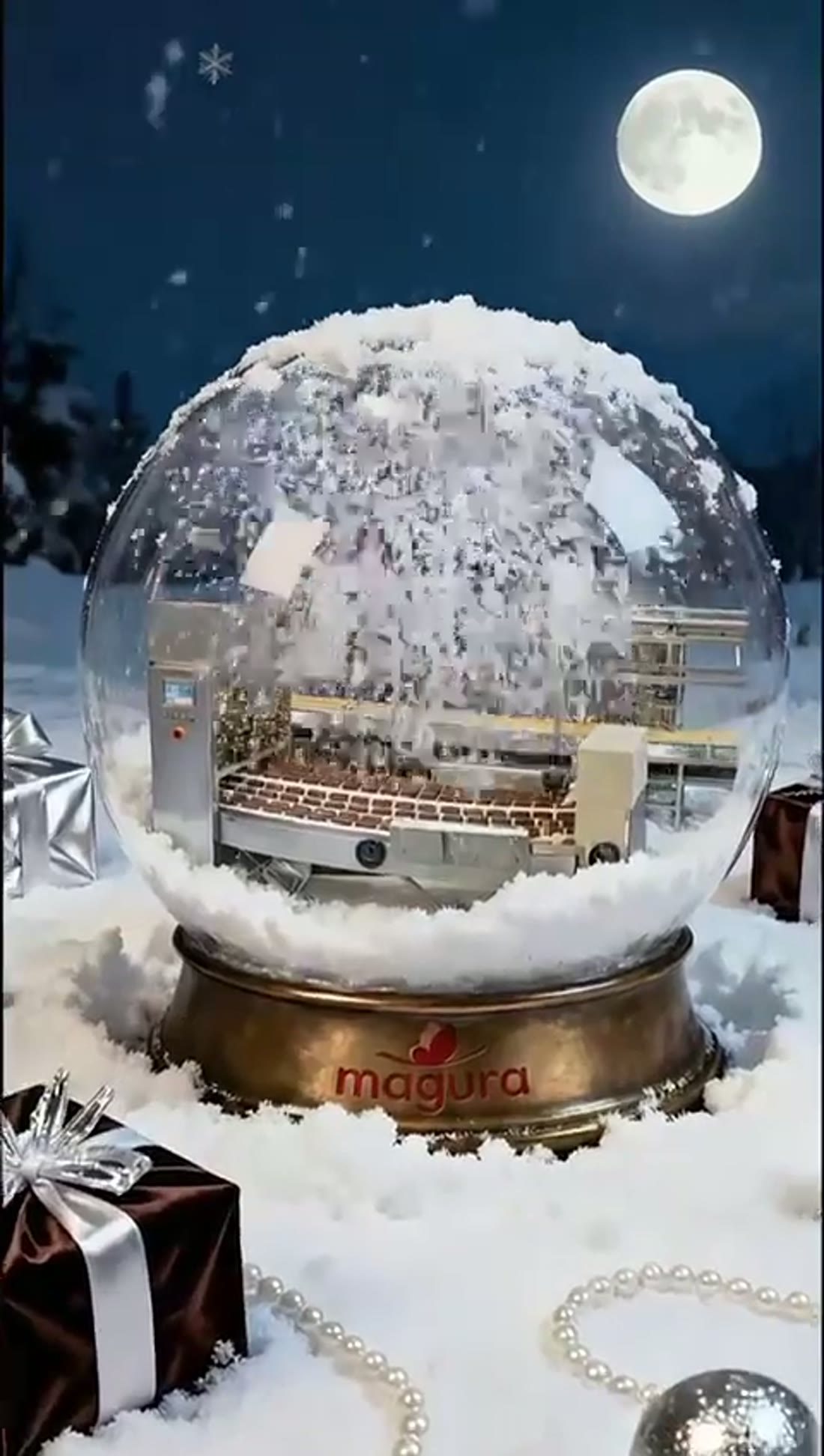 A snow globe holding a lit winter scene, standing in snow beside a wrapped gift under a full moon